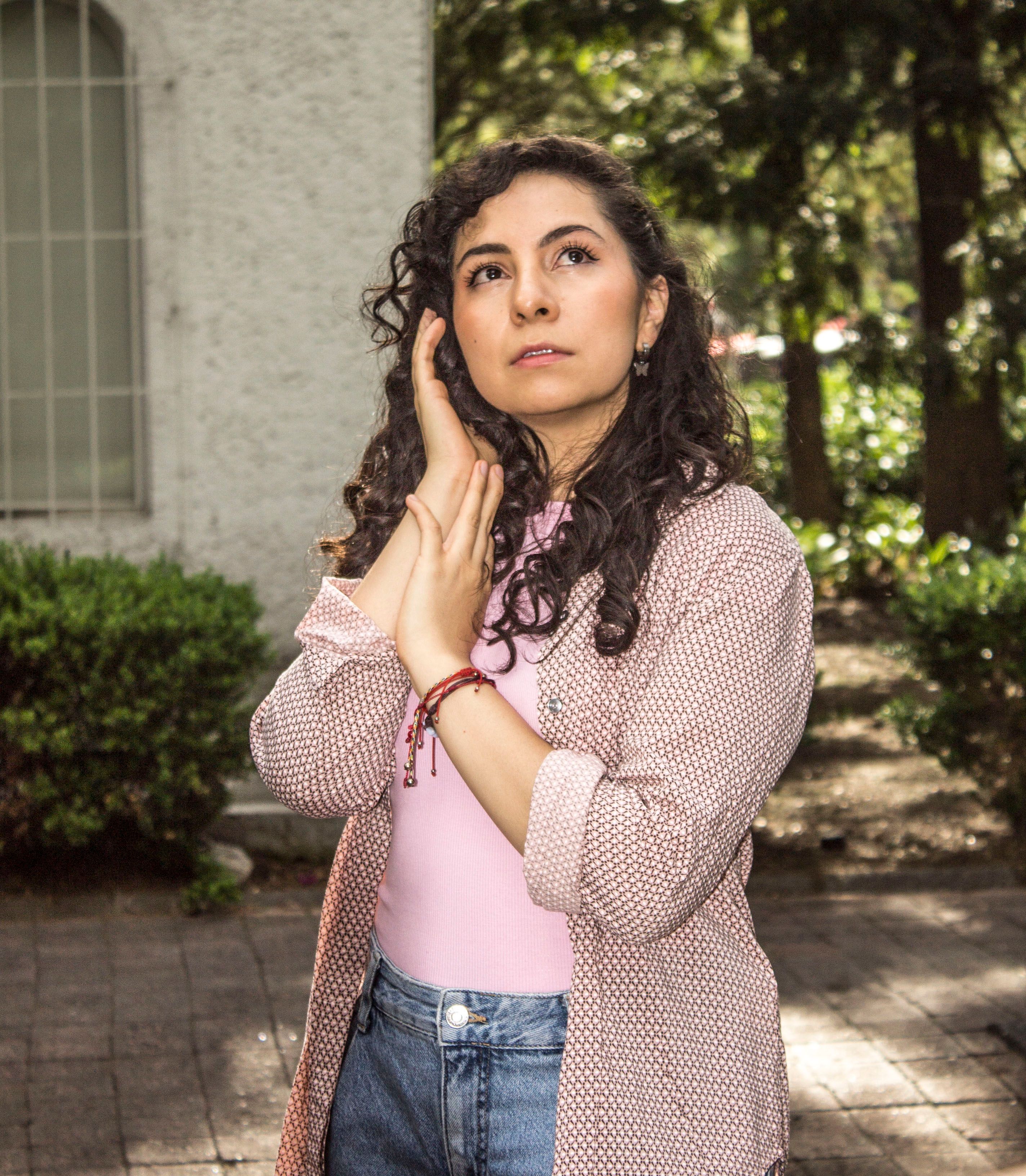 Portrait of a woman in a casual outfit, posing outdoors in daylight.