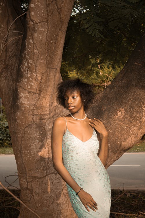 Young Woman in a Dress Standing by the Tree