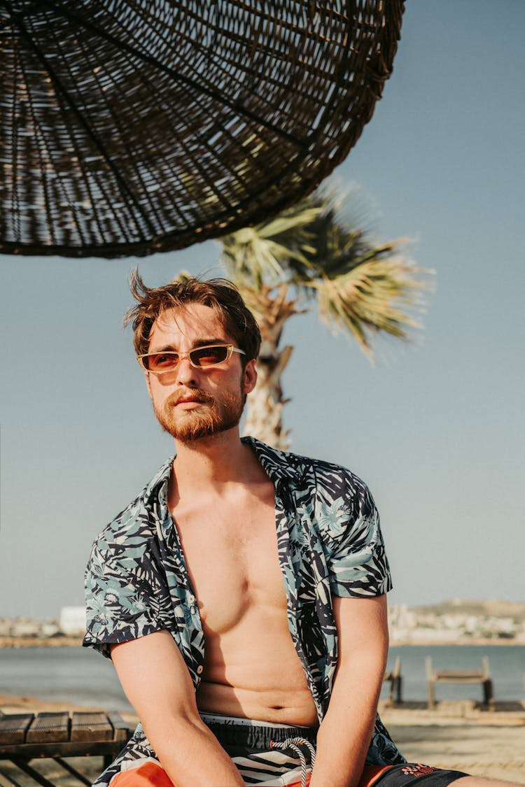 Man In Tropical Shirt Sitting Under Sun Umbrella