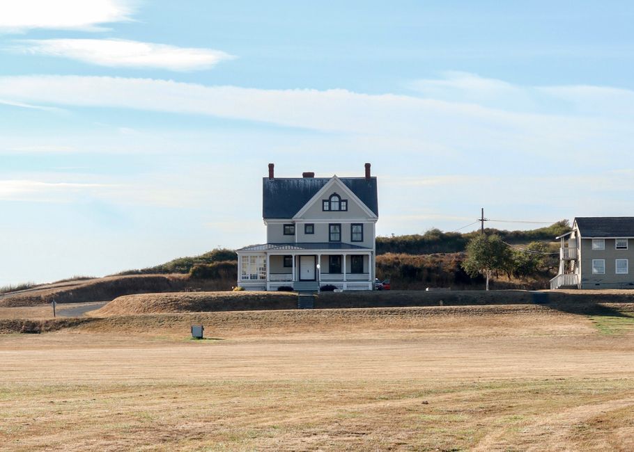 A classic rural home with a peaceful landscape on a sunny day, showcasing countryside tranquility.