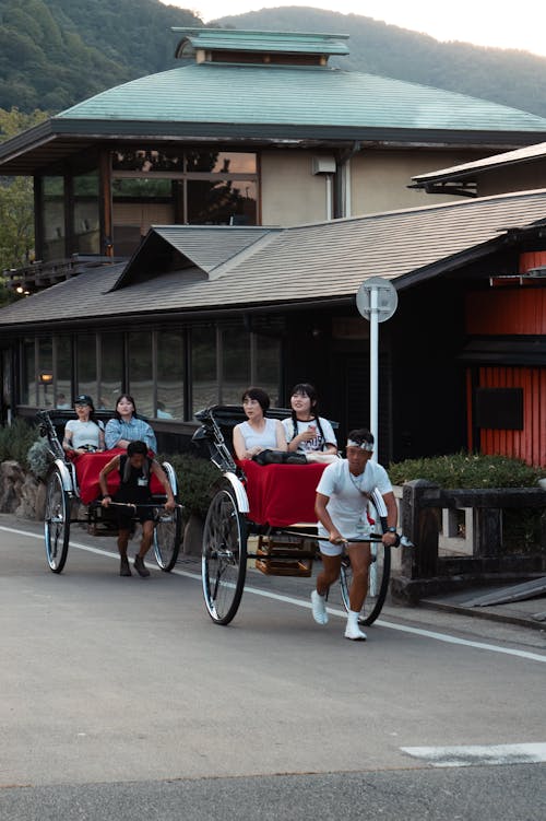 Group of Women Riding Horse Drawn Carriages Dragged By Men