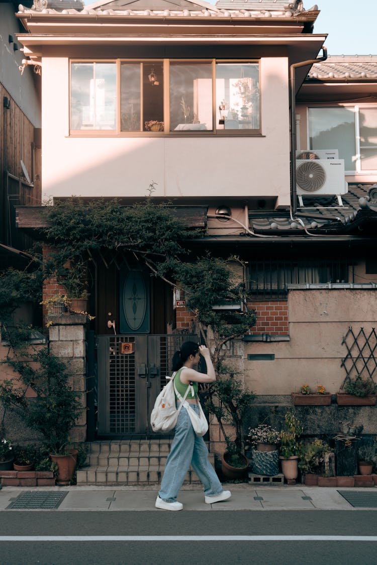 Woman Walking Near House In Town