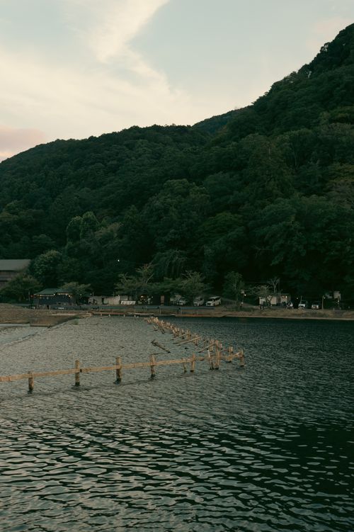Free Lush green hills surround the serene river in Kyoto, Japan, showcasing nature's beauty. Stock Photo