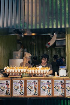 Busy street food stall in Kyoto with Japanese vendors preparing and selling local snacks.