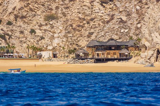 A luxury beachfront hotel nestled against rocky cliffs in Cabo San Lucas, Mexico.