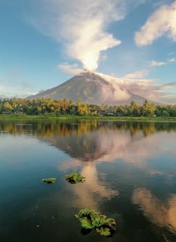 平静的湖水中倒映着美丽的火山日出景色，四周环绕着郁郁葱葱的绿色植物