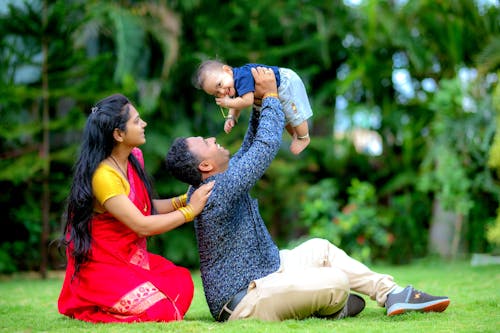 Mother and Father Sitting and Holding Son in Raised Arms