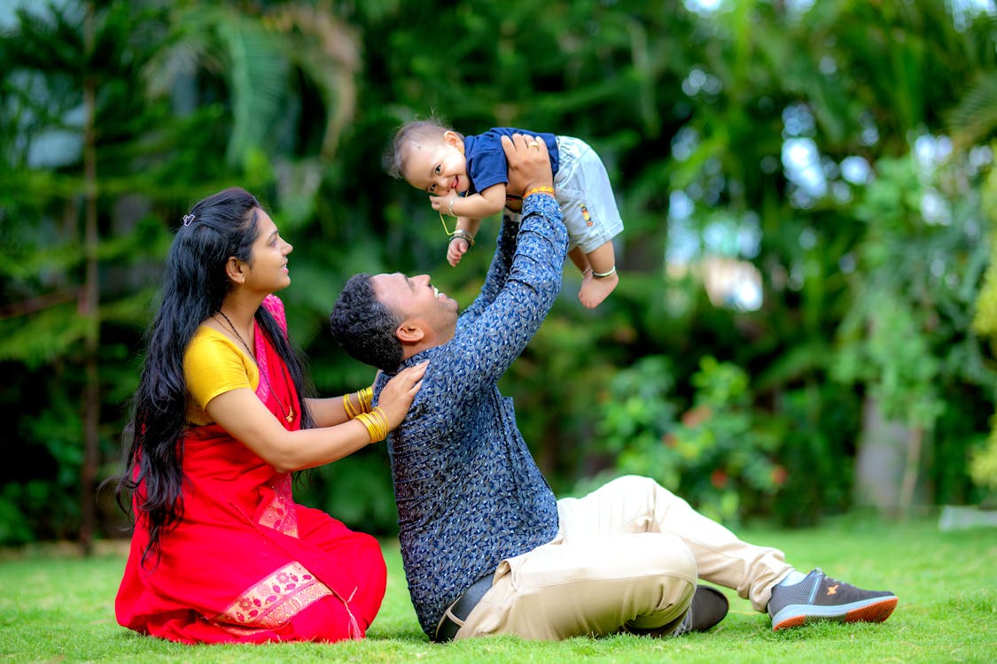 Mother and Father Sitting and Holding Son in Raised Arms