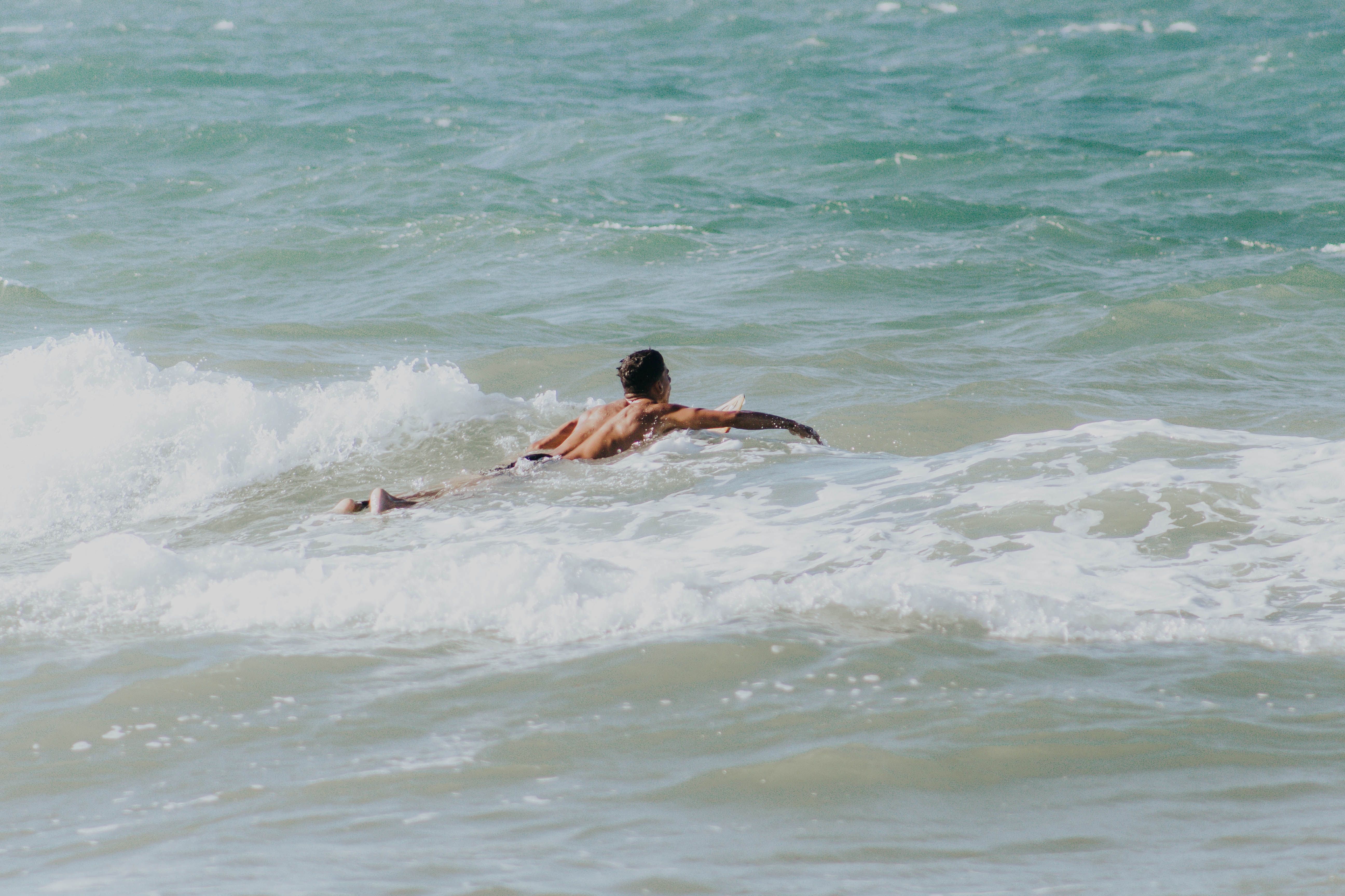 A man enjoys bodyboarding in the vibrant waves of Aracati beach, Brazil.