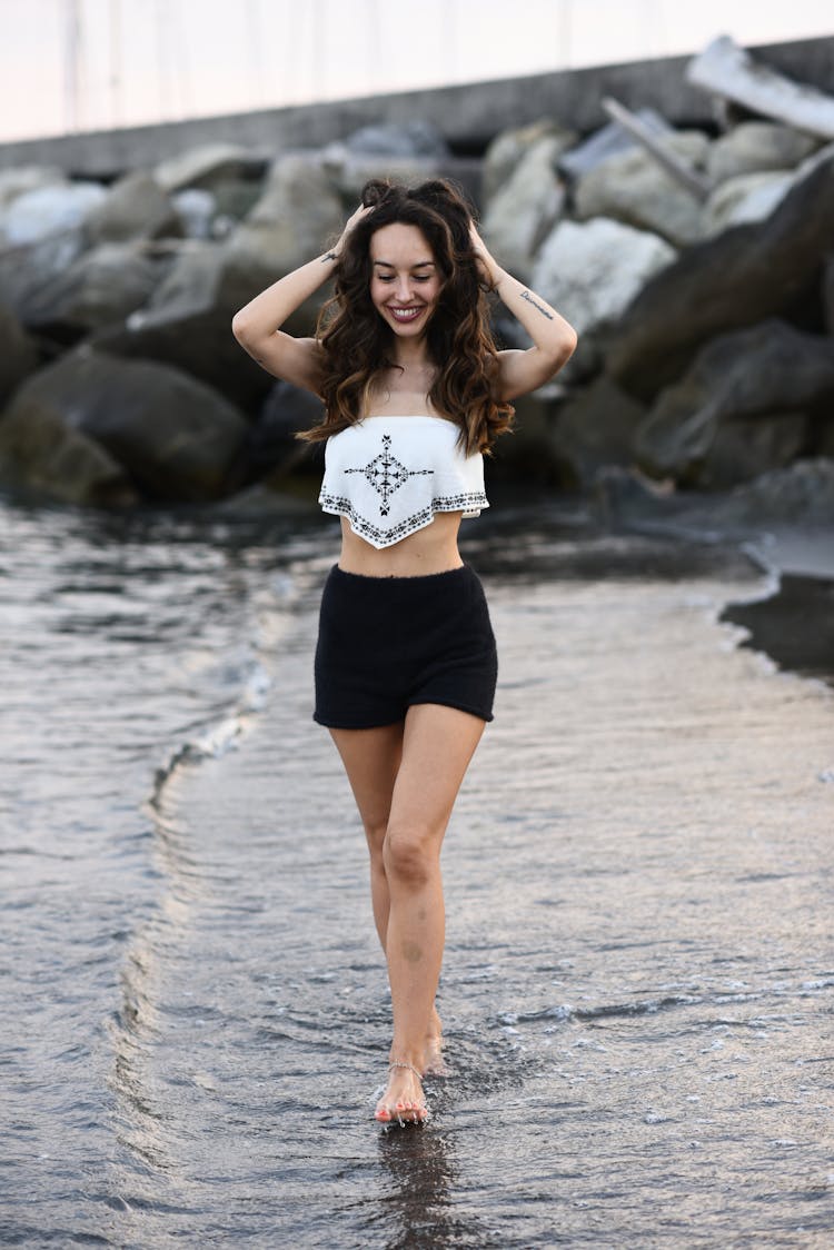 Woman Walking Along The Shore Fixing Her Hair