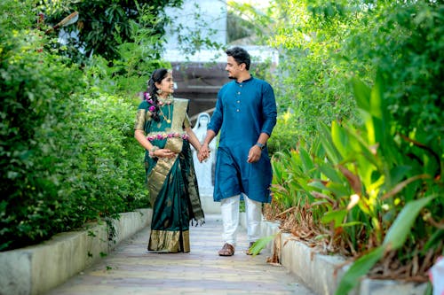 Pregnant Woman and a Man in Traditional Clothing Walking and Holding Hands 