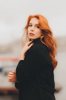 Portrait of a stylish redhead woman outdoors in a black coat.