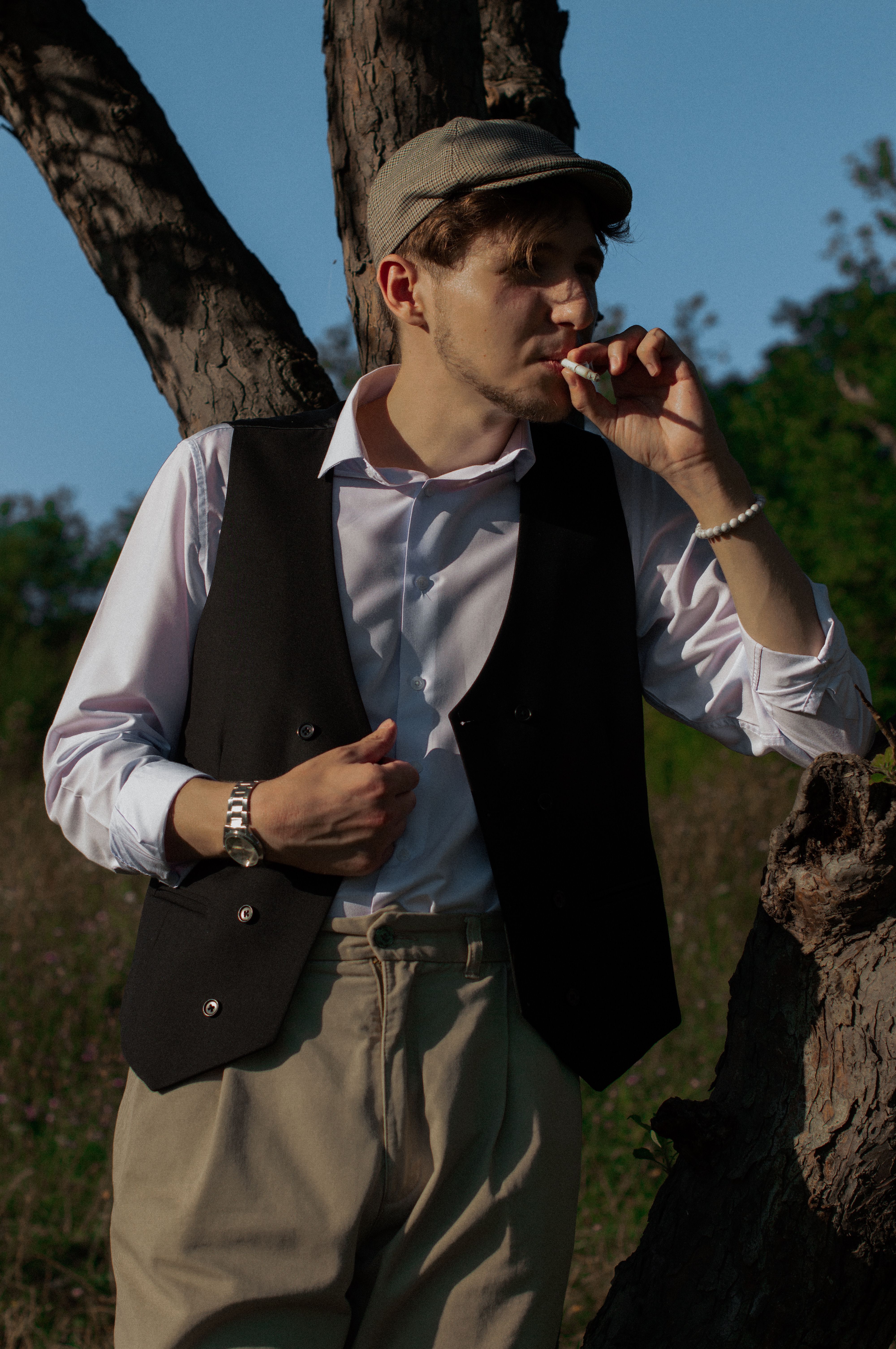 Man wearing waistcoat outdoors by a tree
