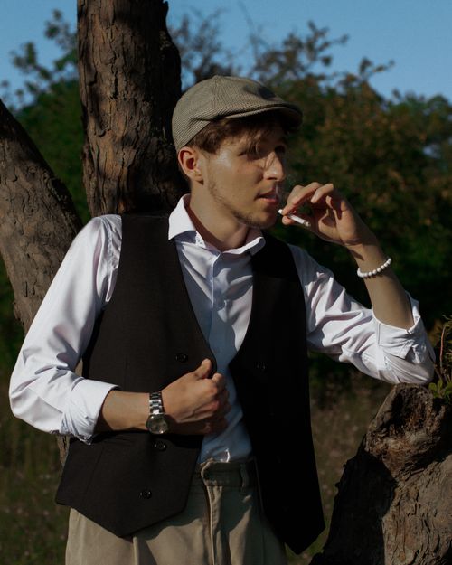 Free Man in a vintage outfit with flat cap and waistcoat, smoking outdoors. Stock Photo