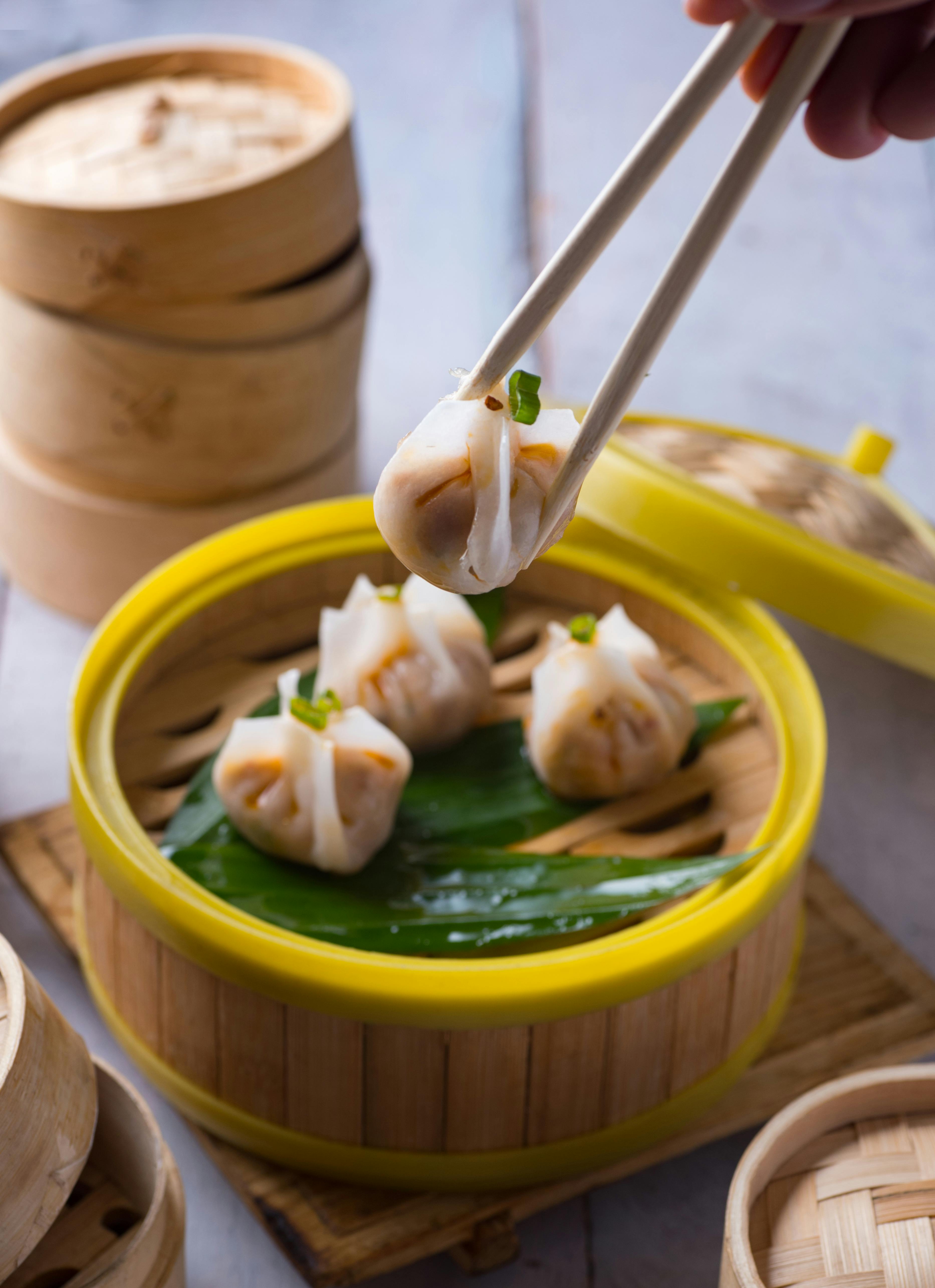 Close-up of translucent har gow prawn dumplings and open-topped siew mai in a bamboo steamer at a dim sum restaurant in Singapore