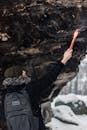 一位冒险家在白雪皑皑的岩石下，用照明弹向冬季荒野发出信号