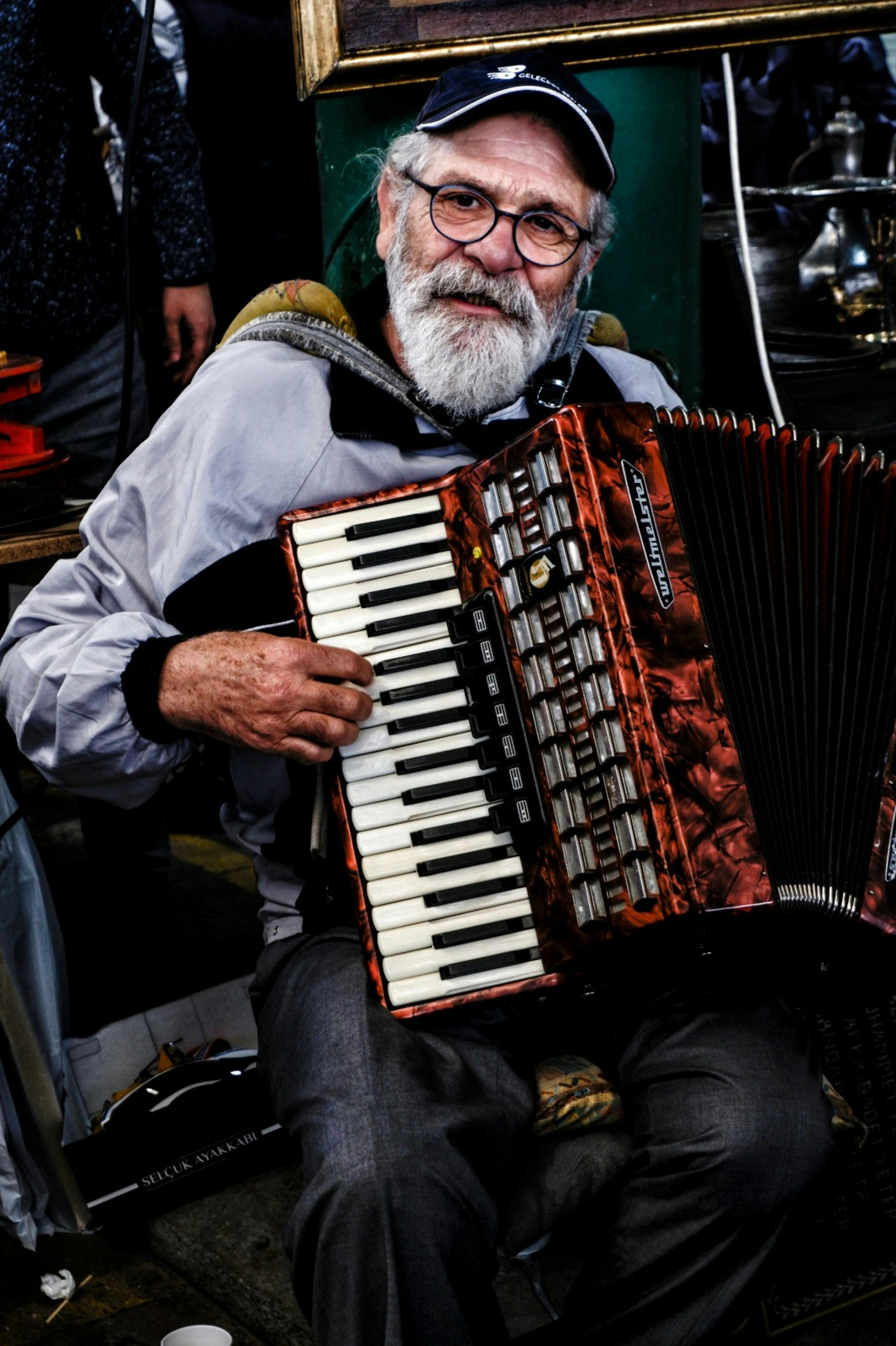 Senior musician joyfully plays accordion, showcasing his passion for music inside a lively setting.
