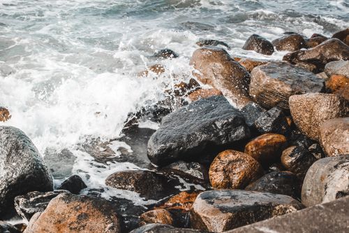 Free Waves crashing onto rocky seashore, creating a vibrant and scenic ocean view. Stock Photo