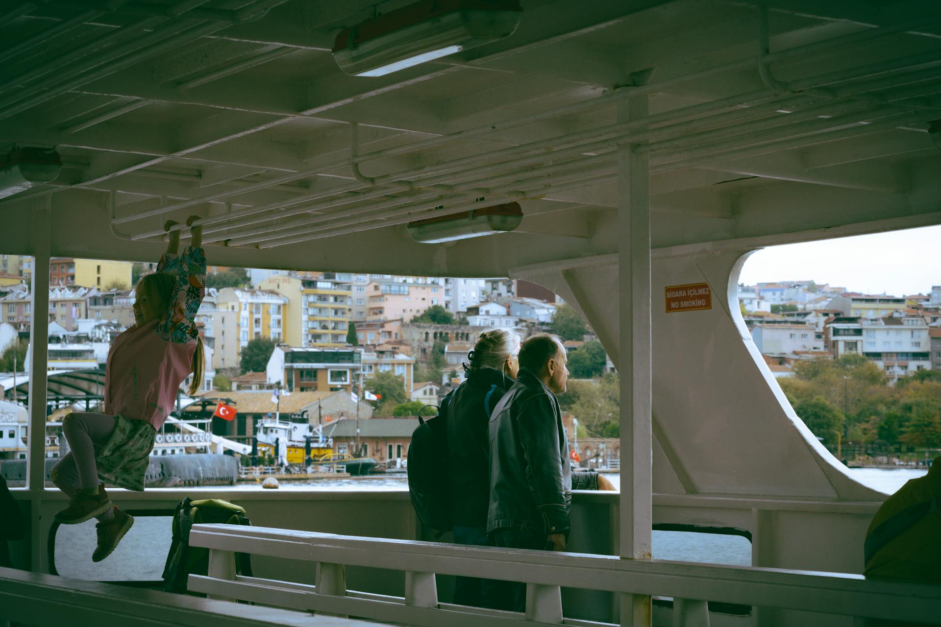 Passengers enjoying a ferry ride with a view of a Turkish cityscape.