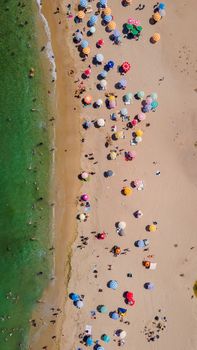 A vibrant aerial shot of a beach in Kıyıköy, Türkiye with colorful umbrellas and sunbathers.