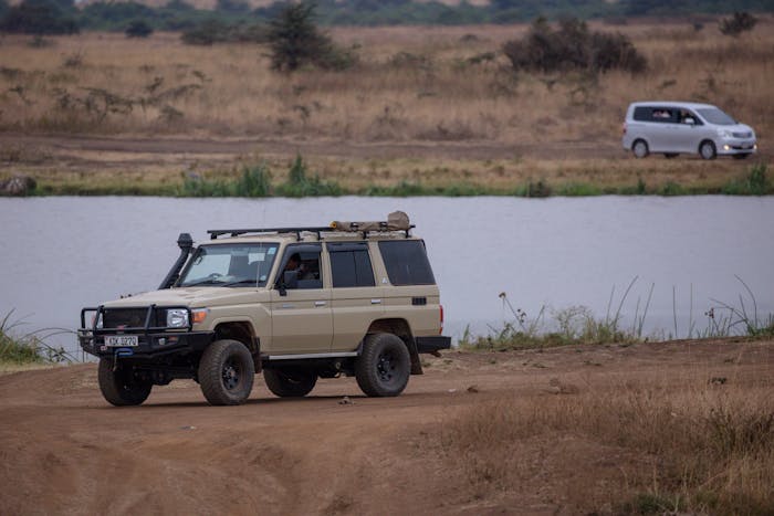 4x4 safari vehicle on a dirt road with Mount Kilimanjaro towering in the background, Tanzania