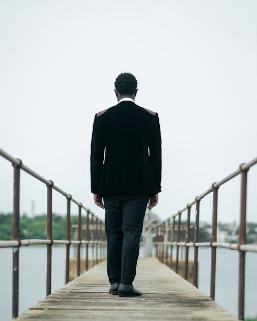 Back View of a Man Standing on a Wooden Pier 