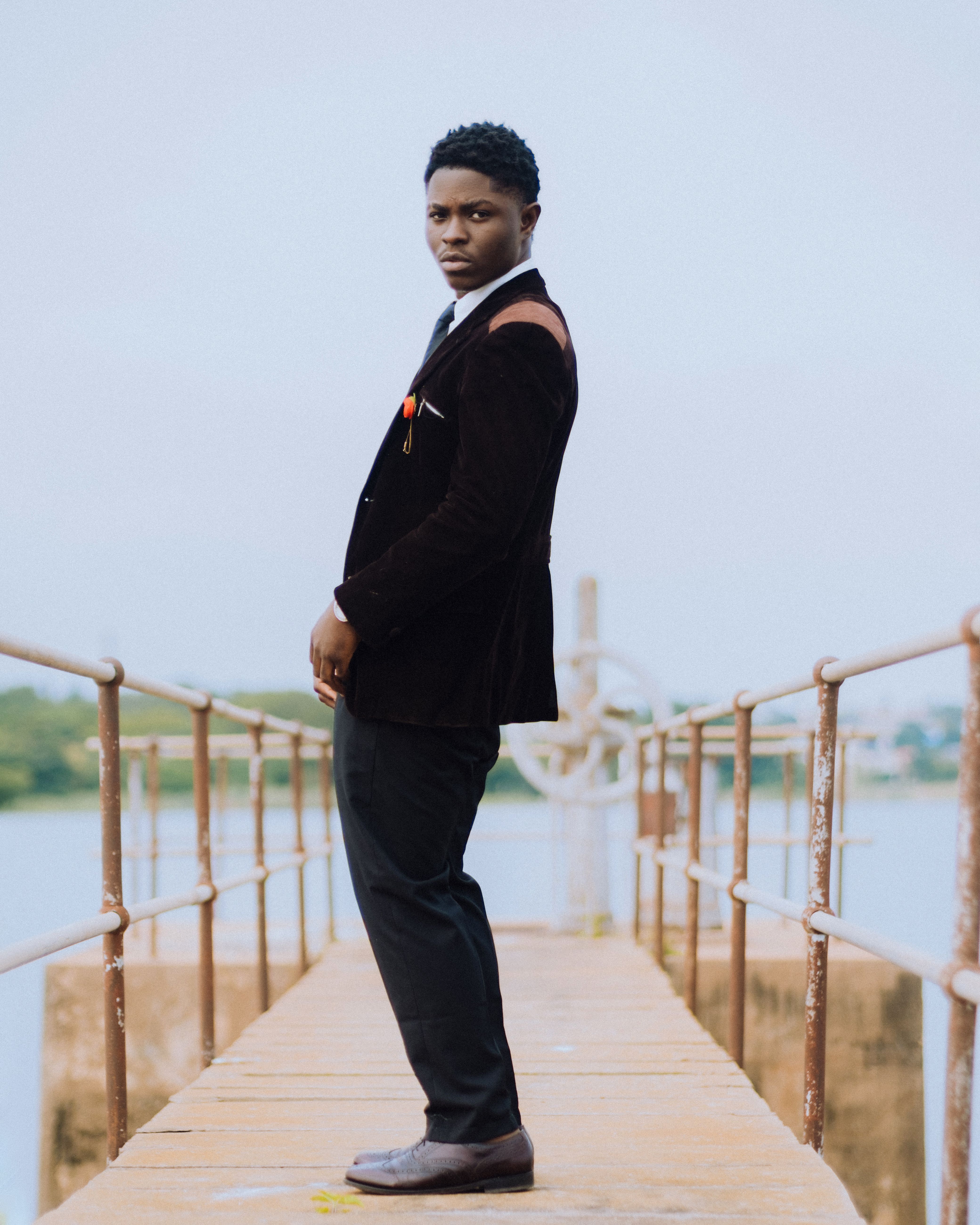 A man dressed in a stylish suit confidently poses on a rustic pier. Perfect for fashion and lifestyle themes.