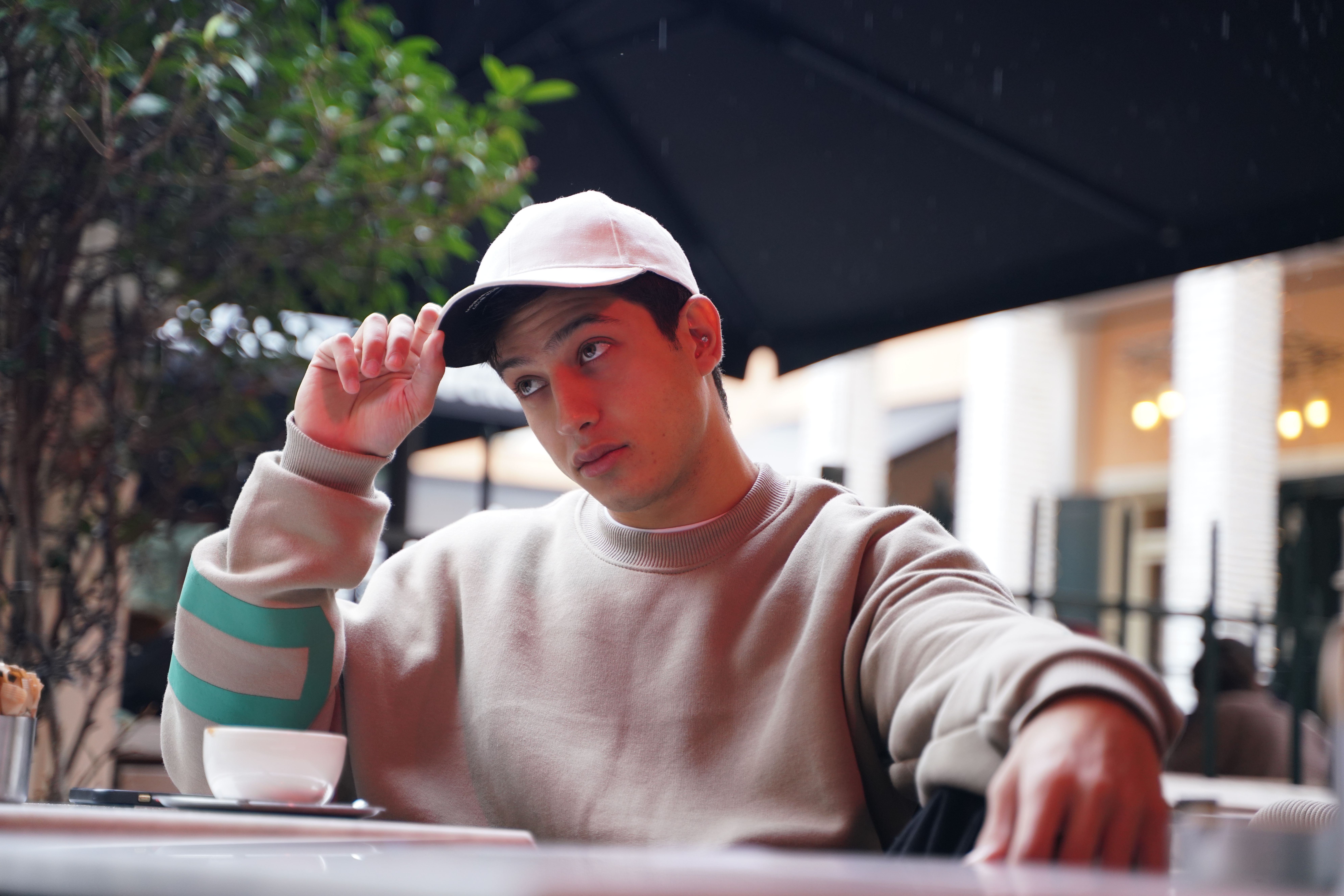 Homme en sweatshirt oversize et casquette rose dans un look streetwear décontracté