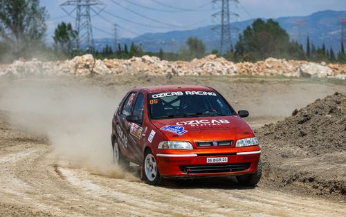 Free A red Fiat racing car speeds around a dirt track corner, kicking up dust behind it. Stock Photo