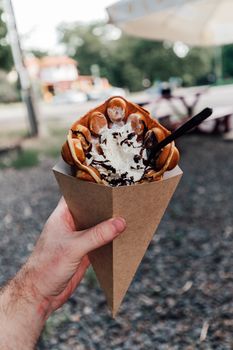 Delicious bubble waffle cone with ice cream held by a hand, perfect for a sweet treat.