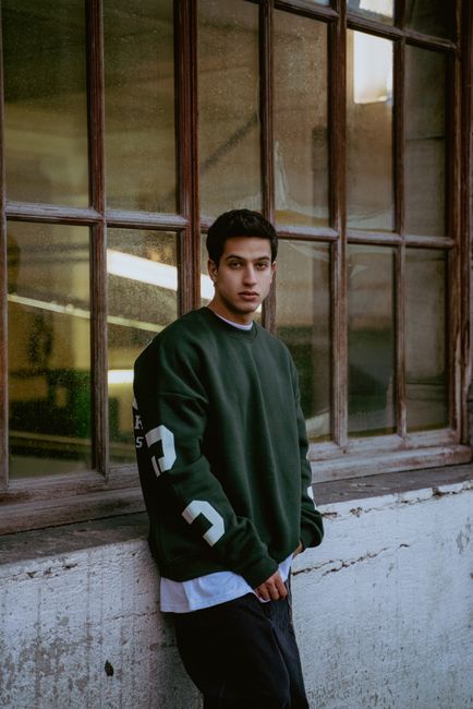 Stylish young man in a casual sweater posing by a window in İstanbul, Türkiye. Modern fashion photography.