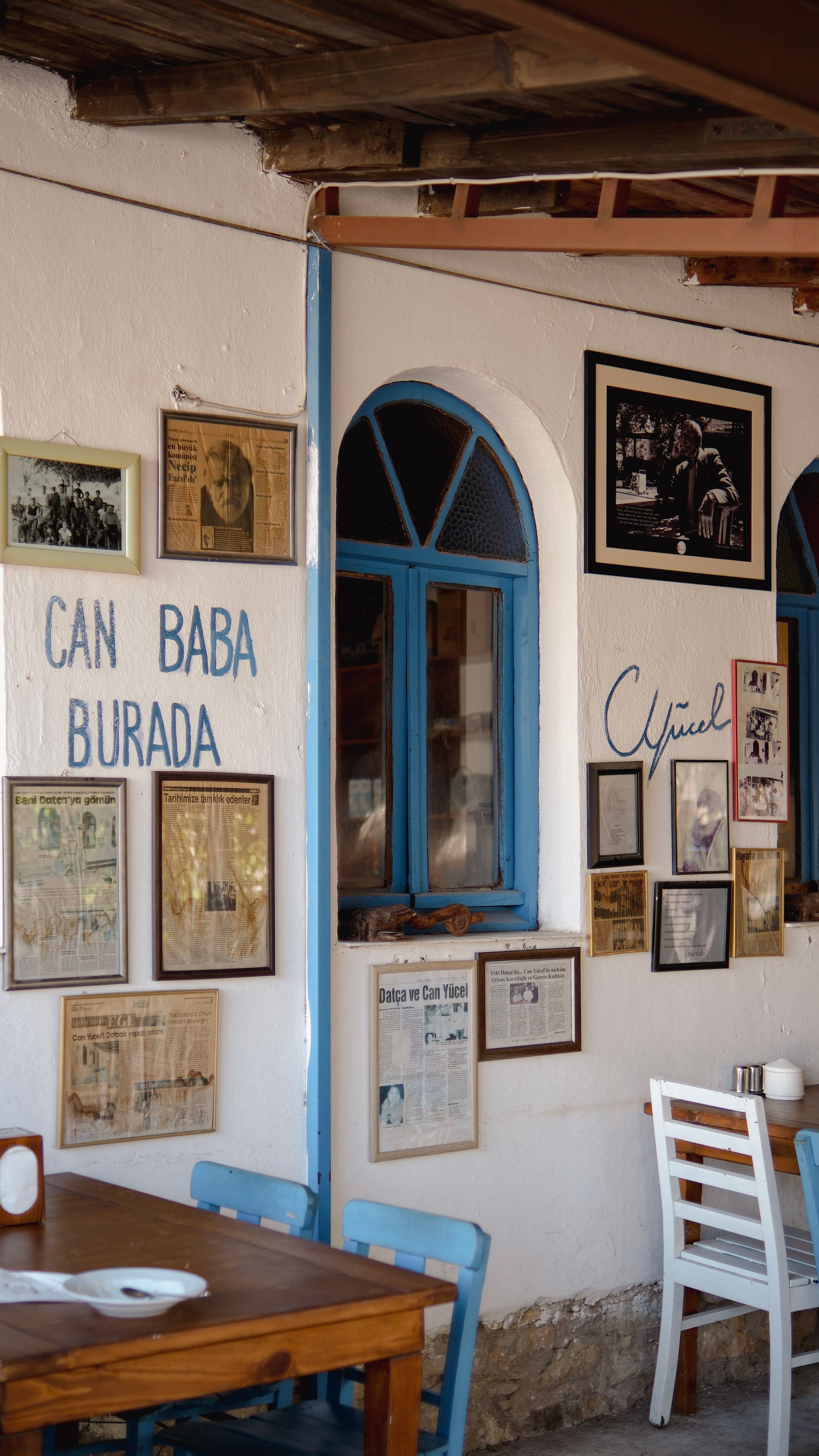 Charming café interior featuring blue arched windows, vintage décor, and framed pictures on white walls.