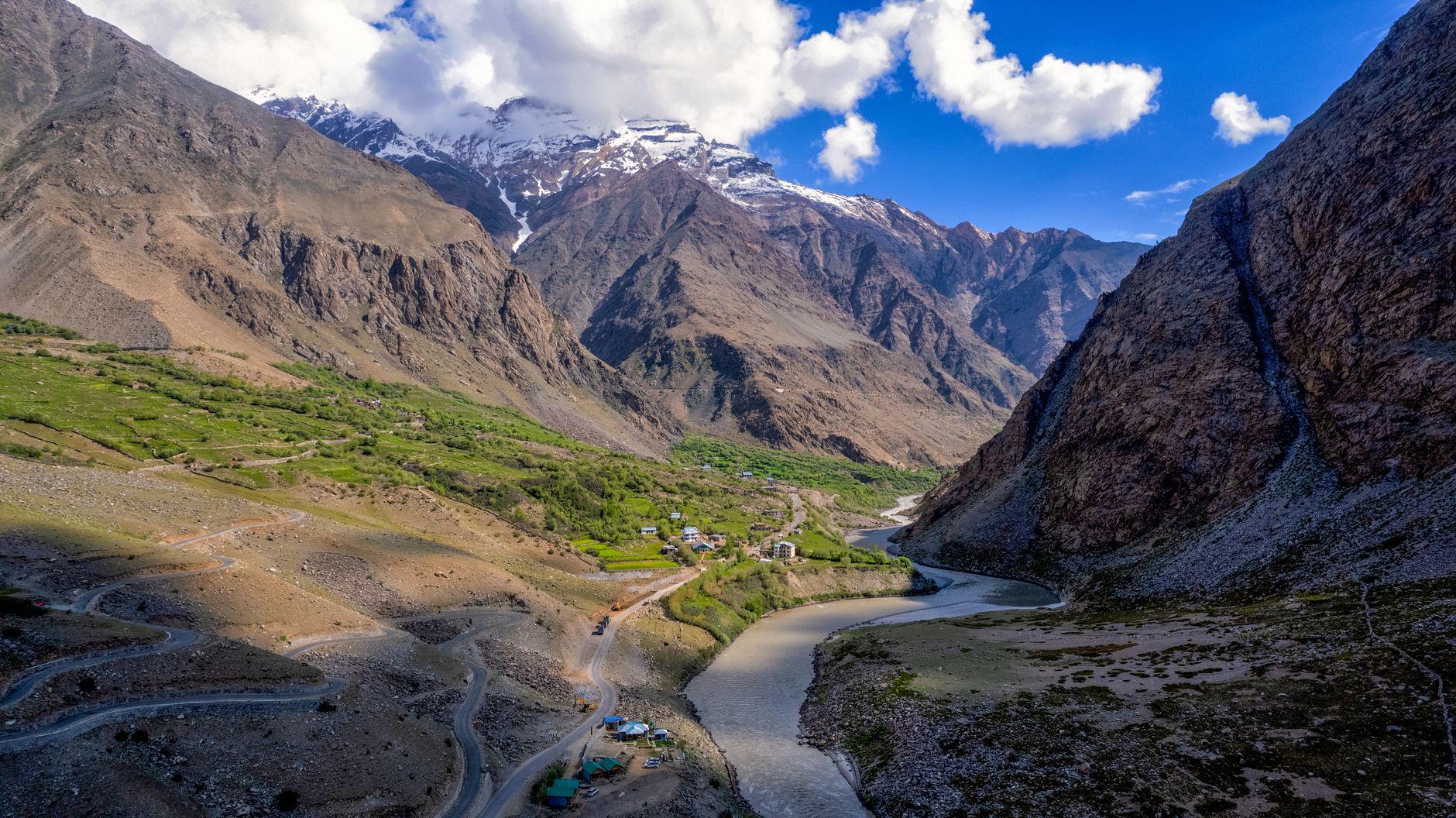Majestic scenery of Zanskar Valley with winding river and towering mountains under a vibrant blue sky.