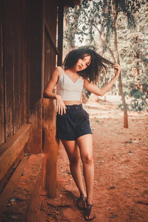 Young Woman in Shorts and Tank Top Playing with her Hair 