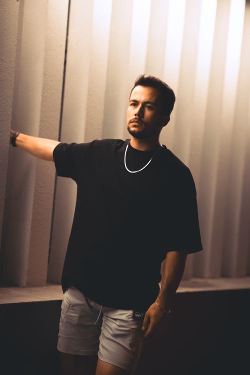 Free Fashion portrait of a man in a black t-shirt posing indoors with dramatic lighting. Stock Photo