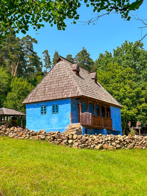A blue house with a wooden roof sitting on top of a hill