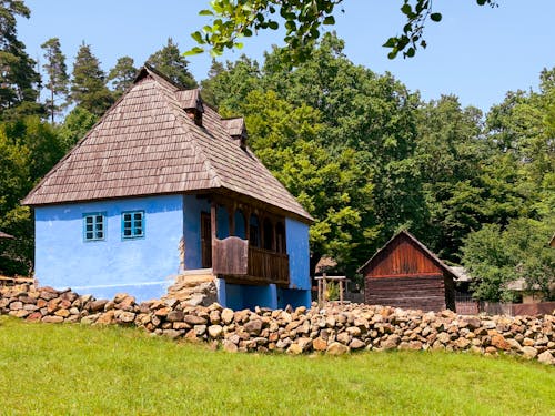 A blue house with a stone wall and grass