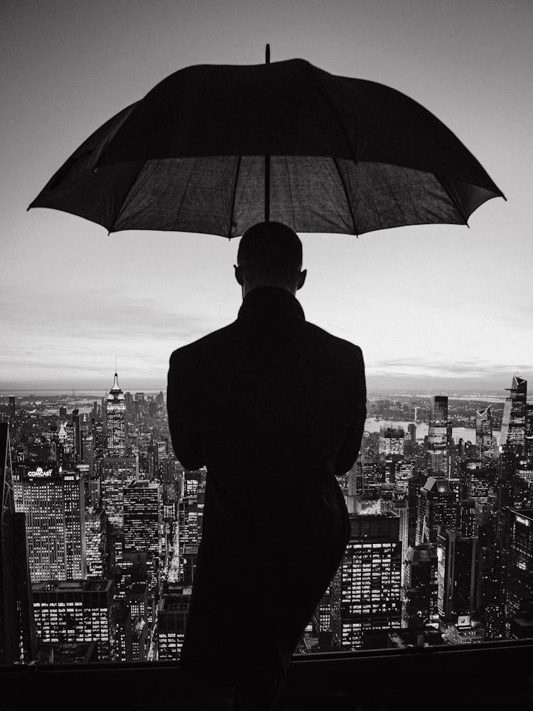 Silhouette Of Man With Umbrella Over City