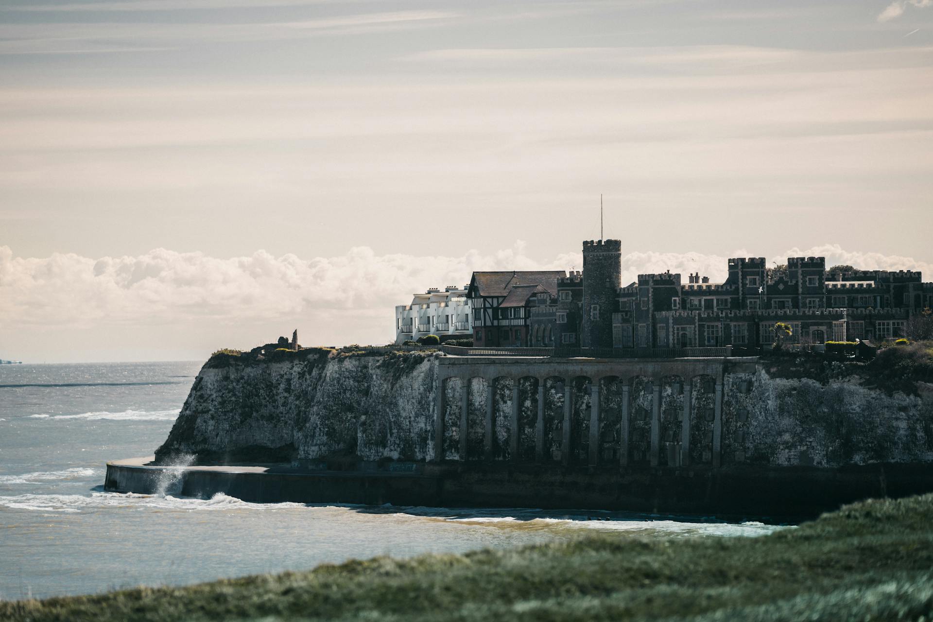 Dramatic view of Kingsgate Castle perched on a cliff overlooking the sea, capturing historical architecture and coastal beauty.