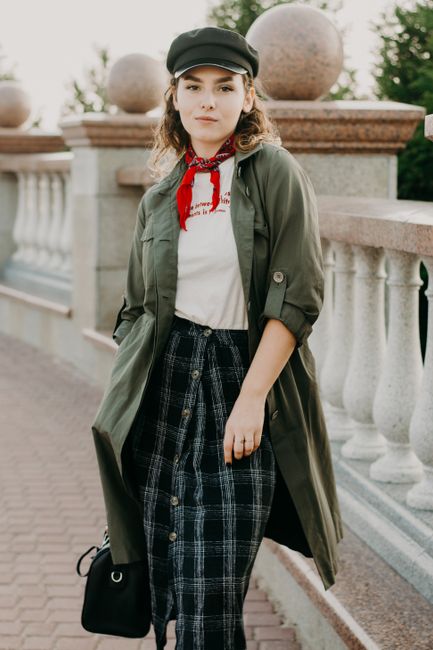 Young woman posing outdoors in chic casual attire with a confident expression.