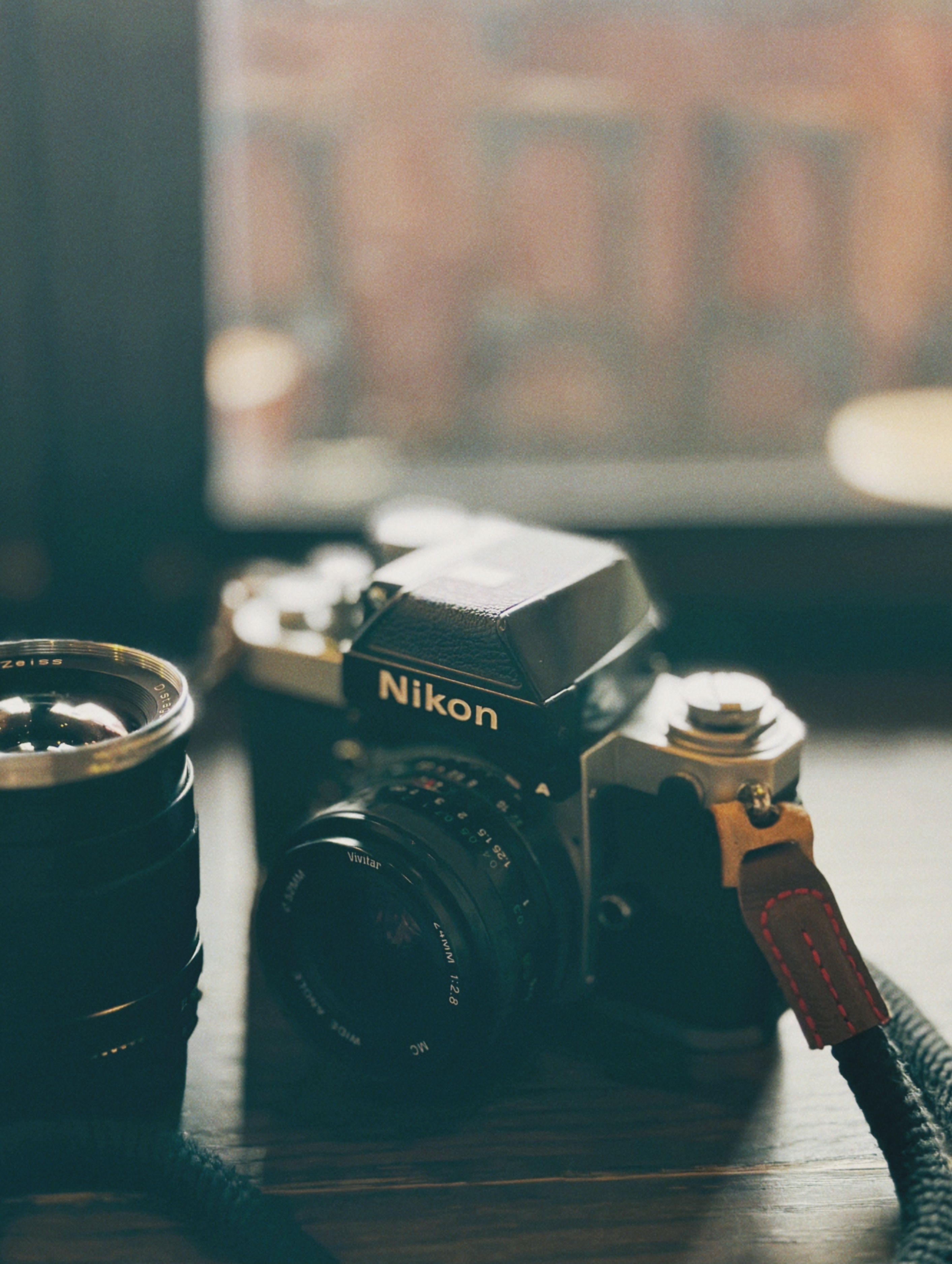 Classic Nikon camera with lens on wooden surface. Perfect for vintage photography lovers.