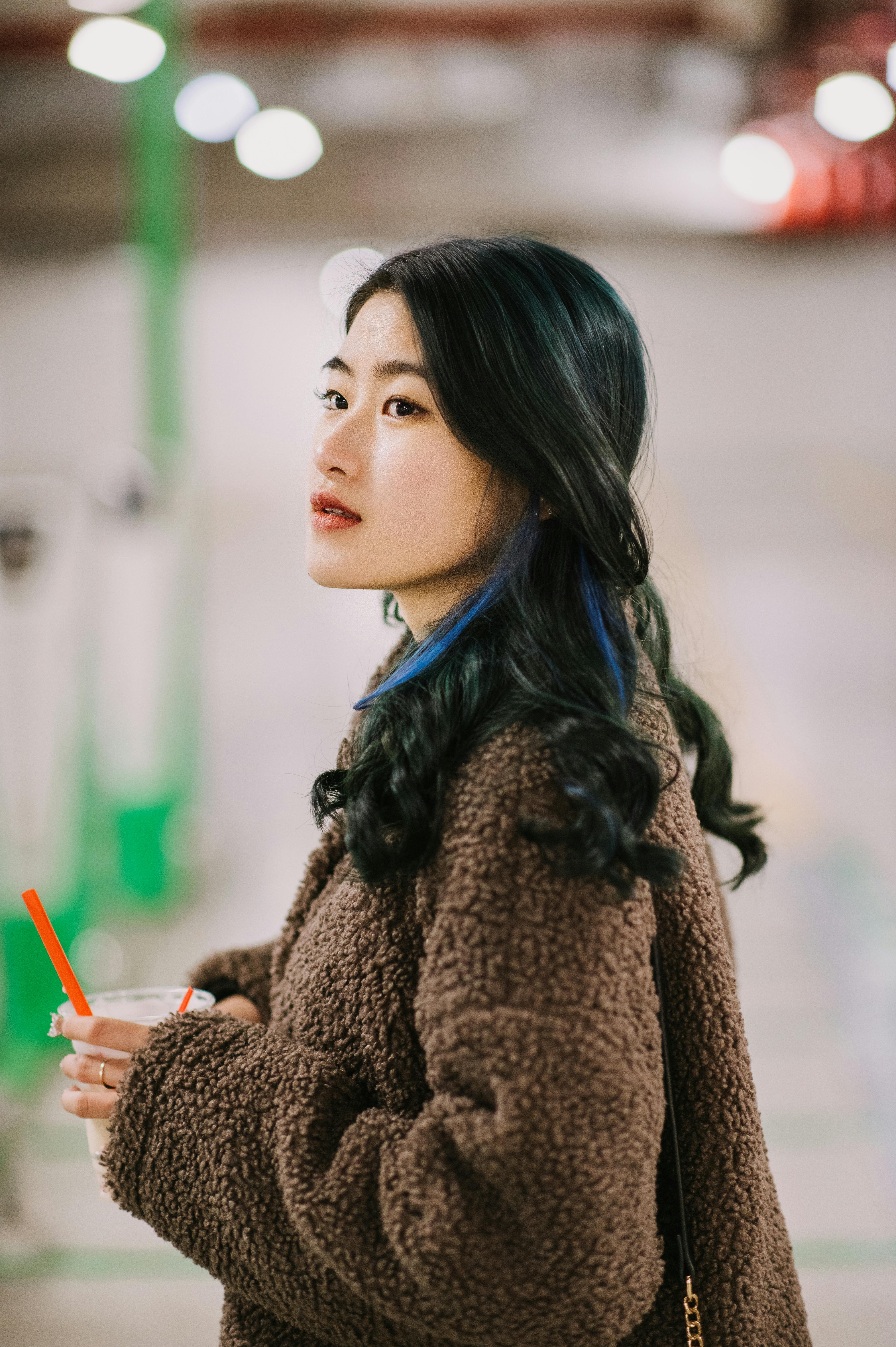 Stylish young woman with drink in urban setting, exuding casual fashion appeal.