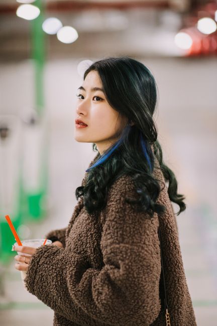 Stylish young woman with drink in urban setting, exuding casual fashion appeal.
