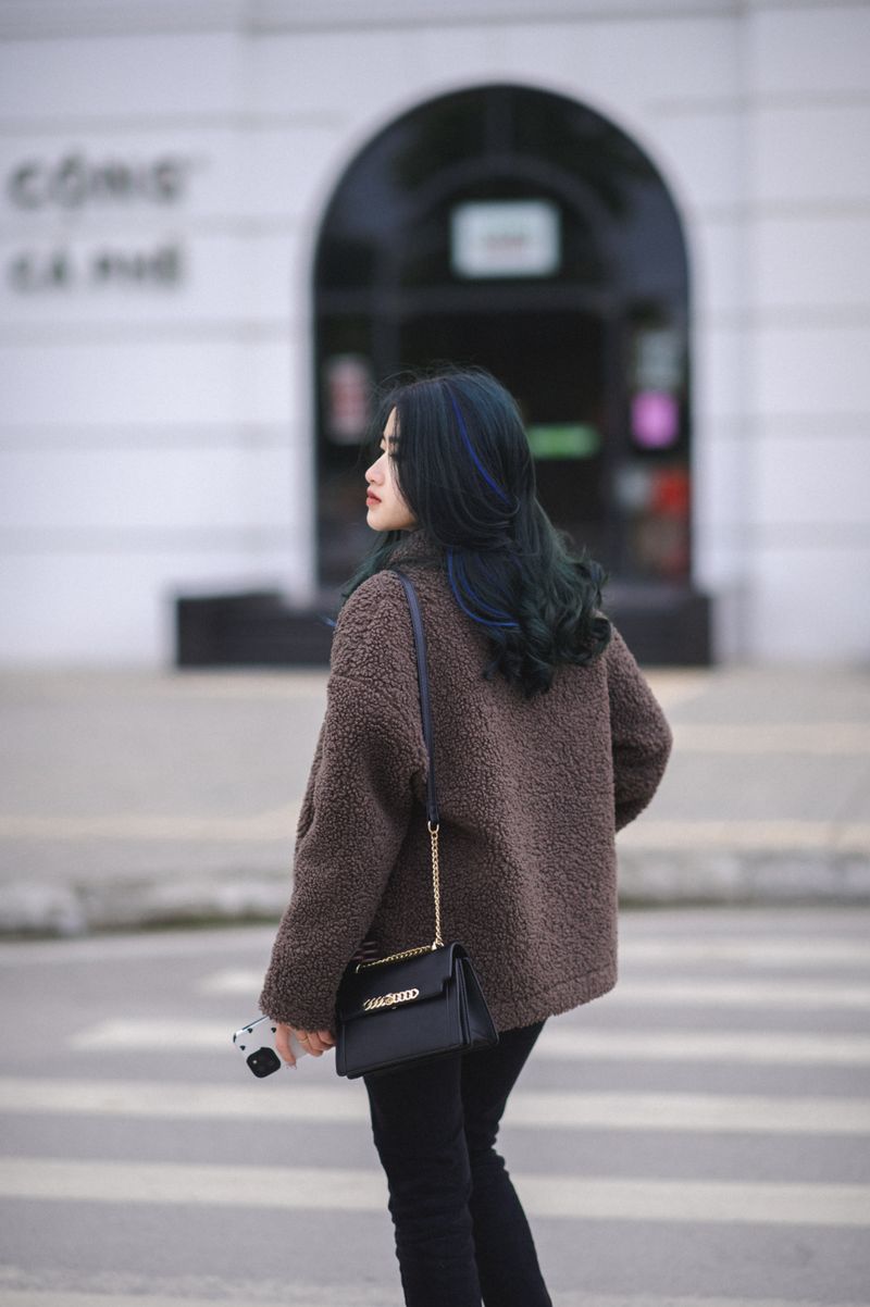 Woman in brown teddy jacket crossing a city street