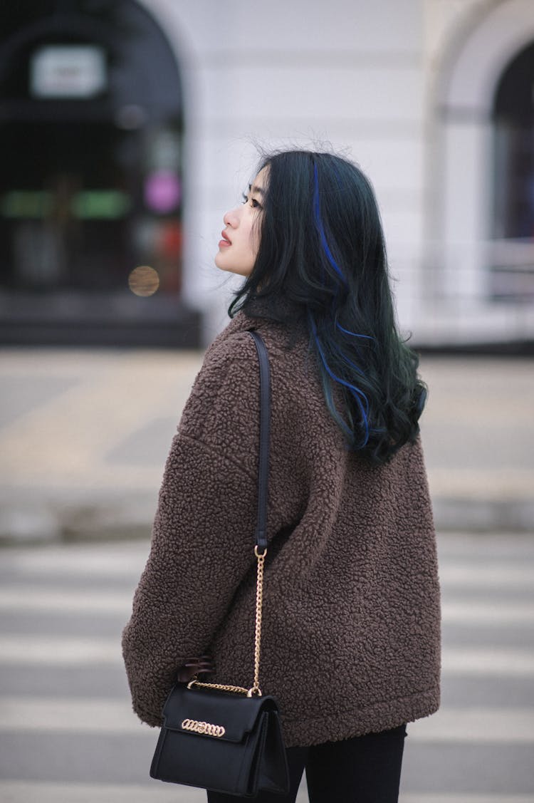 Young Woman In A Brown Jacket Walking In City 