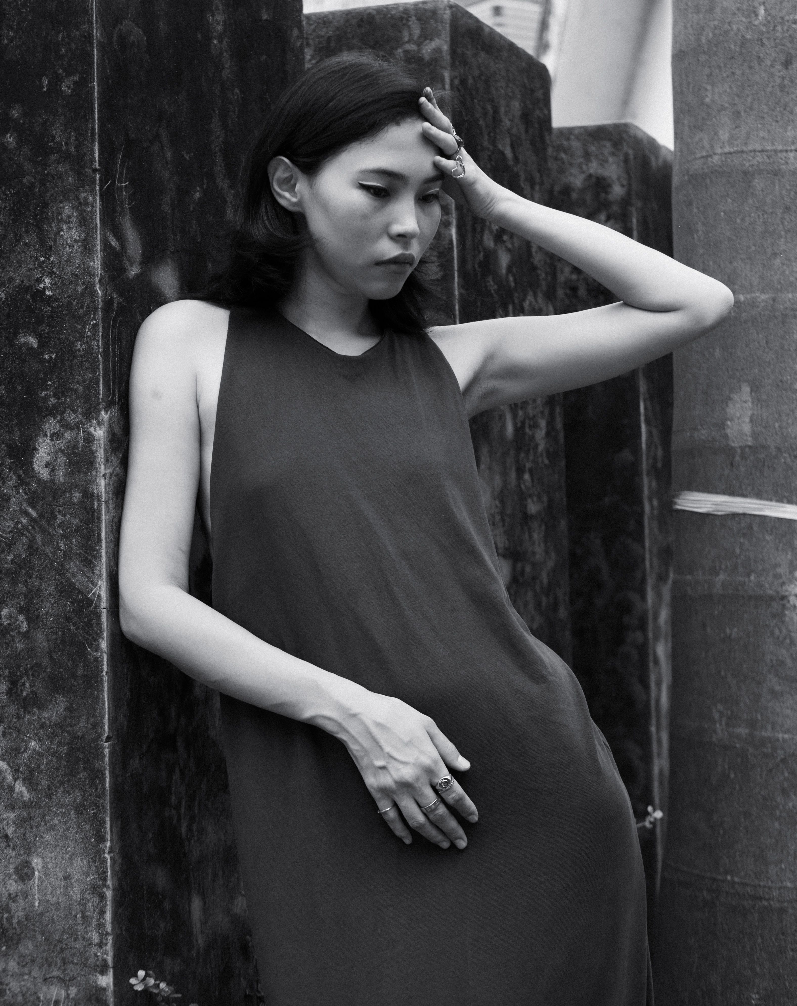 A woman in a black dress leaning against a wall · Free Stock Photo
