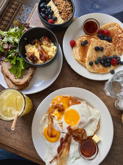 Free A tempting brunch spread featuring pancakes with berries, eggs with bacon, and fresh salad. Perfect brunch idea. Stock Photo