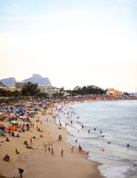 A lively beach scene in Rio with tourists enjoying the summer sun and sand.