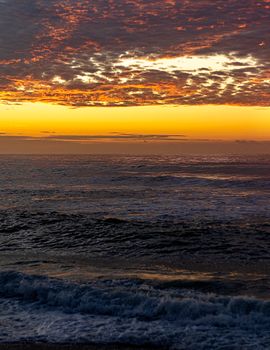 Stunning sunset over ocean waves in Rio de Janeiro, Brazil, with a vibrant yellow sky.