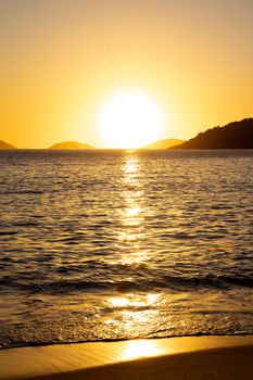 Stunning sunset at a Rio de Janeiro beach with golden reflections on the sea, serene and picturesque.